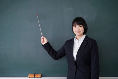 japanese female teacher points to the blackboard in the classroom