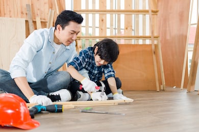 father, a carpenter, teaches his son to hammer nails.