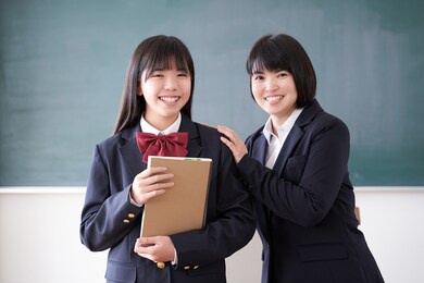 a japanese junior high school girl and her teacher stand in the classroom with a smile