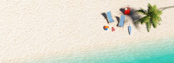 aerial view of sandy beach and ocean and beach chair with beach ball flip-flop sandals, umbrella and suit case under a palm tree at the beach during a summer vacation in the caribbean, with copy space