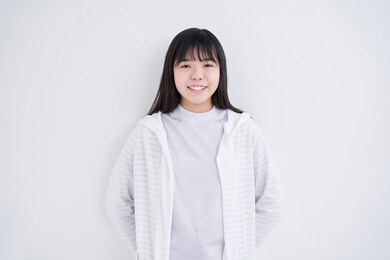 a japanese junior high school girl stands in a white background with a smile