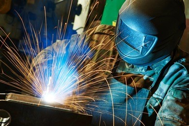 welder working with electrode at semi-automatic arc welding in manufacture production plant