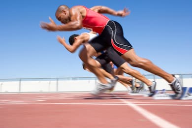 young male sprinters starting a sprint race from their starting blocks on a bright, sunny day at the track