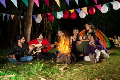 happy indian asian friends playing music and enjoying bonfire or campfire in nature
