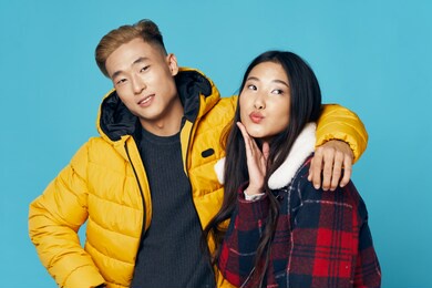 fashionable young couple of asian appearance in winter clothes hugs studio 