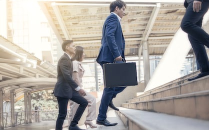 focusing on business man wearing blue formal suit, holding briefcase, hurry and rush running on the steps while going to work in the early morning