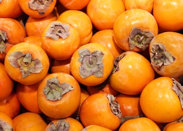 ripe orange persimmons. on the table in the market. a bunch of organic persimmon fruits at a local farmers market. persimmon background. flat lay. copy space for text and content.