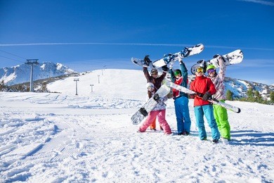 five friends holding snowboards and skies together