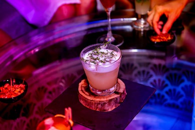 cold drink in the glass cup on the round wooden. a cocktail in the bar at night club for alcohol and colorful party concept.