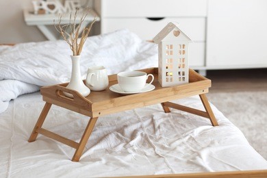 wooden tray with coffee and interior decor on the bed with white linen