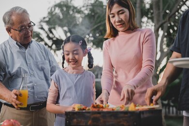 asian family having a barbecue party at home. cooking grilled bbq for dinner in backyard. lifestyle on summer holiday.
