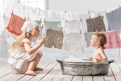 skinny little girl in a basin for washing clothes in the laundry room