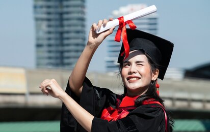 women in graduation gowns hold diplomas have happy and success on university campus outdoors with sunshine, graduate with diploma. graduate feeling happy after receiving long awaited master diploma.