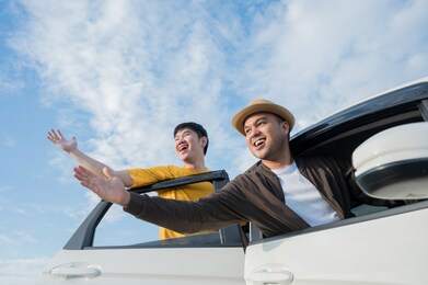 two asian friends travel by car on a clear day, beautiful blue sky. they was happy along the way trip.