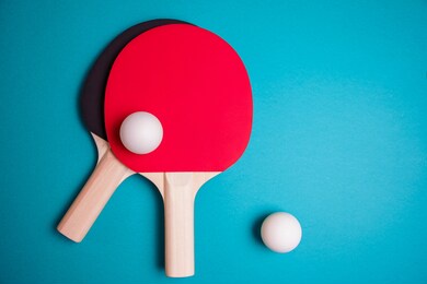 table tennis or ping pong rackets and ball on the blue table. background, shallow dof.