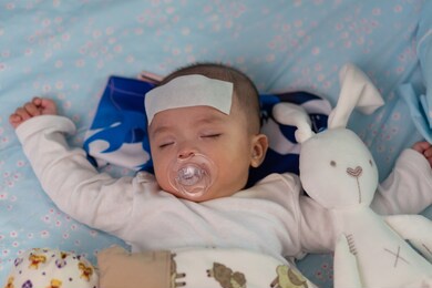 asian chinese baby sleeping during high fever with cool fever jel pad on forehead