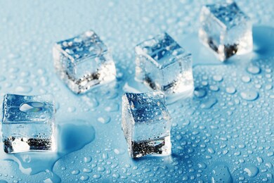 close-up ice cubes with melt water drops scattered on a blue background.