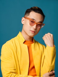 trendy guy in orange glasses on a blue background and a yellow jacket