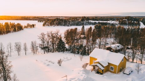 aerial view from drone of frozen lake covered by white snow near small cozy village with colorful houses on north, bird’s eye view of lapland countryside land with scenery environment 
