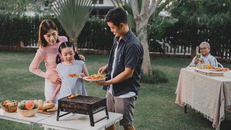 asian family having a barbecue party at home. cooking grilled bbq for dinner in backyard. lifestyle on summer holiday.
