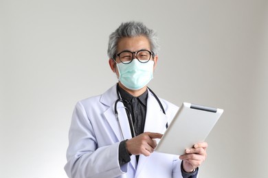 the senior asian physician with mask on the white background.