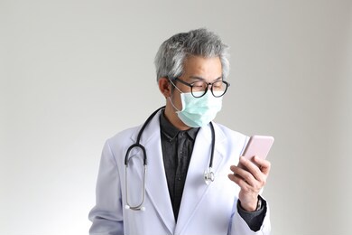 the senior asian physician with mask on the white background.