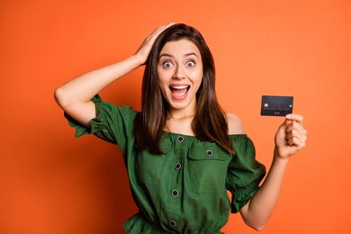 photo of impressed funny lady wear green off-shoulders blouse arm head holding bank card isolated orange color background