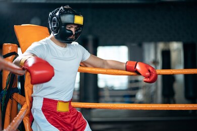 tired athletic sport man boxer resting in corner boxing ring after fighting