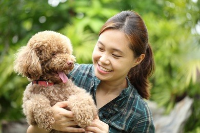 asian girl hug with her poodle dog in the garden