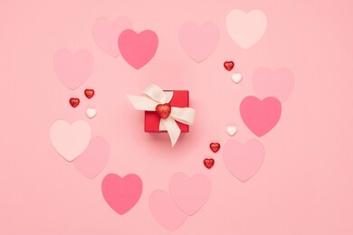 pink paper hearts and red gift box on pastel pink background. valentines day concept. flat lay, top view, copy space. festive holiday greeting card for valentines, birthday, woman or mothers day.