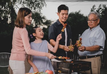asian family having a barbecue party at home. cooking grilled bbq for dinner in backyard. lifestyle on summer holiday.