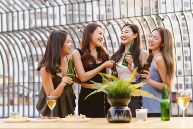 asian girls gang drinking beer while enjoying rooftop bar party. group of friends having fun at terrace party.concept about women night out.