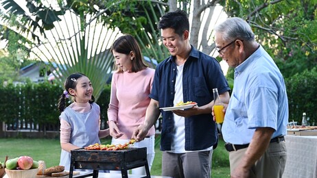 asian family having a barbecue party at home. cooking grilled bbq for dinner in backyard. lifestyle on summer holiday.