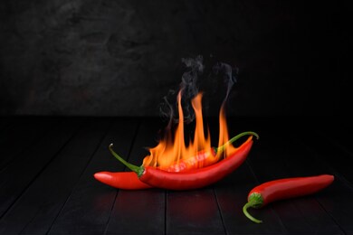 red chili peppers were burned with a hot burning flame. placed on the old dark wood floor concept spicy and hot