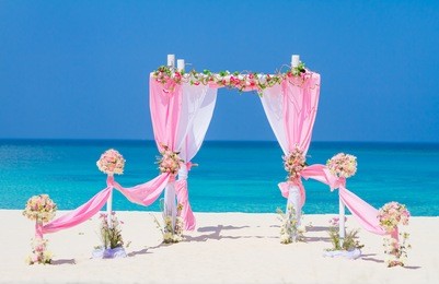 wedding arch decorated with flowers on tropical sand beach, outdoor beach wedding setup