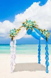 wedding arch decorated with flowers on tropical sand beach, outdoor beach wedding setup