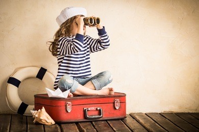 happy kid playing with toy sailing boat indoors. travel and adventure concept. child, summer, vacation