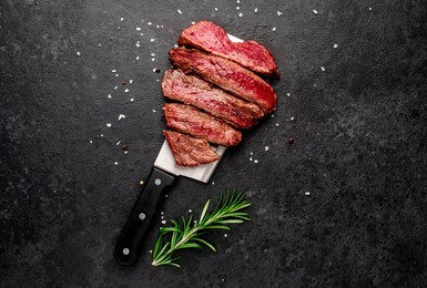 different degrees of roasting heart shaped beef steak with spices on a meat knife on a stone background with copy space for your text