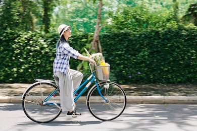 happy young chinese woman enjoying riding on bicycle in park, blurred motion