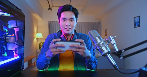 asian man have live stream and playing mobile game on the smartphone at home