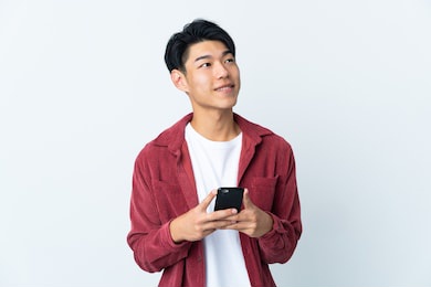 young chinese man isolated on white background using mobile phone and looking up