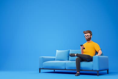 cartoon smiling beard hipster man in yellow t-shirt and glasses seat on sofa and using smartphone over blue background. 3d render illustration.
