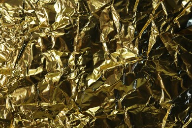 abstract gold foil texture. crumpled metal background with yellow tint and gradient. horizontal photo for festive design. template for banner, poster with copy space for holiday and congratulations