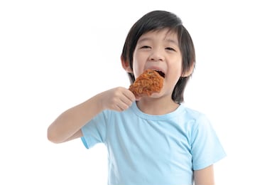 cute asian child eating fried chicken on white background isolated