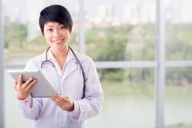 young asian doctor standing with a digital tablet