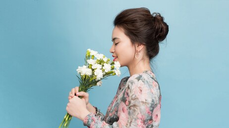 valentine's day - dreaming voluptuous young woman with bouquet of flowers while standing against blue background