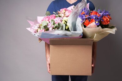 white male courier holding a large cardboard box with several bouquets, . high quality photo