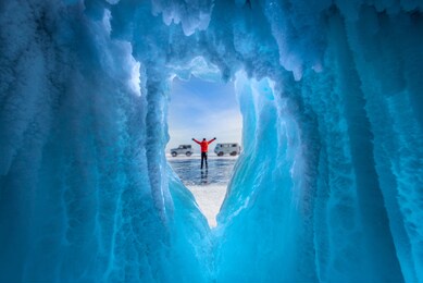 traveller man raise up hand freedom and enjoy view of beautiful landscape natural breaking ice in frozen cave at lake baikal, siberia, russia. travel or freedom concept.