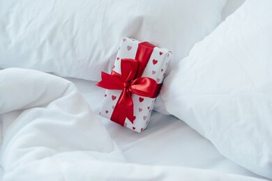 gift box packed and decorated with a bow on the bed. valentine's day gift.