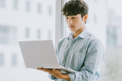 asian businessman is using laptop to work by window

